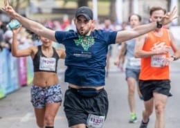 Runner excitedly crosses the 2019 Austin Half Marathon finish line. Run Austin, the #1 city in America and you will understand why people love the Austin Marathon!