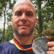 run-the-world-feature Image of Jonathan Acott showing off his medal from the Berlin Marathon. Read about his journey to run the world and how the Austin Marathon is next!
