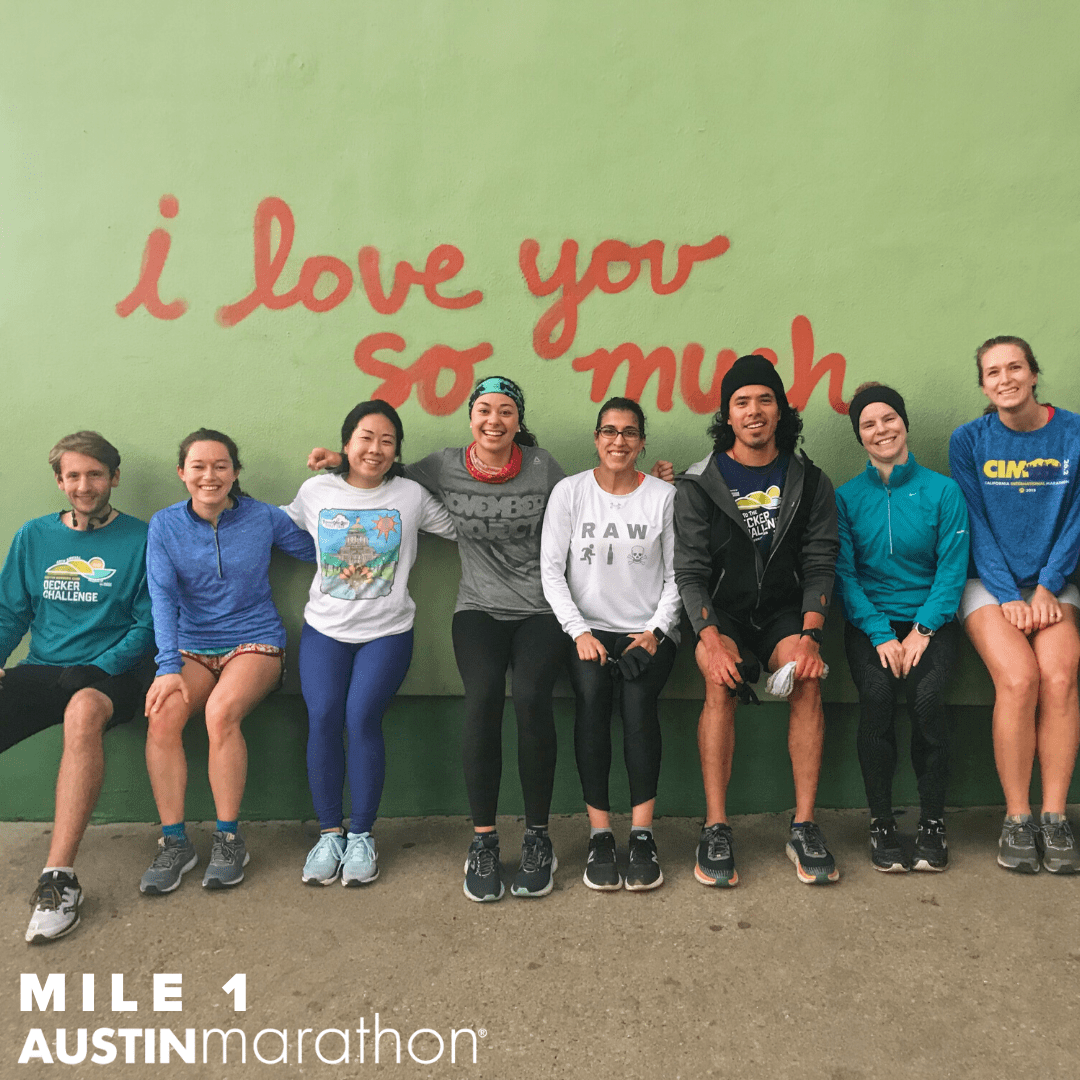 Image of i love you so much mural in Austin with runners from The Morning Jos posing. It's one of the Austin Marathon's favorite on-course murals.