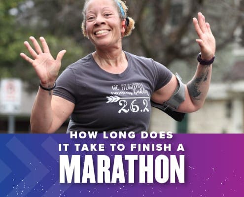 Female runner excitedly raises her hands in the air for the on-course photographer during the 2020 Ascension Seton Austin Marathon. Text on the design reads How Long Does it Take to Finish a Marathon. More information, including a helpful pace chart, can be found at https://youraustinmarathon.com/how-long-will-it-take-you-to-finish-a-marathon/