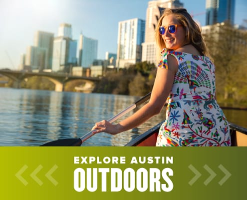 Female smiles while kayaking on Town Lake, one of the many amazing outdoor spaces in Austin. Read more at https://youraustinmarathon.com/outdoor-spaces-in-austin/