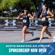 Two women excitedly run towards the finish of the Austin Marathon.