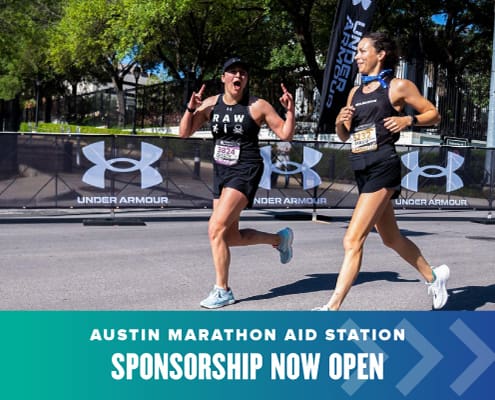 Two women excitedly run towards the finish of the Austin Marathon.