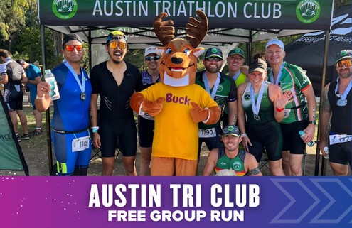 A group of smiling triathletes poses with a person in a Buck the Deer mascot costume under an "Austin Triathlon Club" tent during Austin Tri Club launch week. Text below reads: "Austin Tri Club Free Group Run. Austin Marathon Half Marathon & 5K