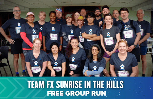 A diverse group of smiling runners in “Team FX” shirts pose indoors, some with race bibs. A banner reads: "TEAM FX SUNRISE IN THE HILLS @ MULESHOE - FREE GROUP RUN." Join us to train for the Austin International Half or just get out and Run Austin!. Austin Marathon Half Marathon & 5K