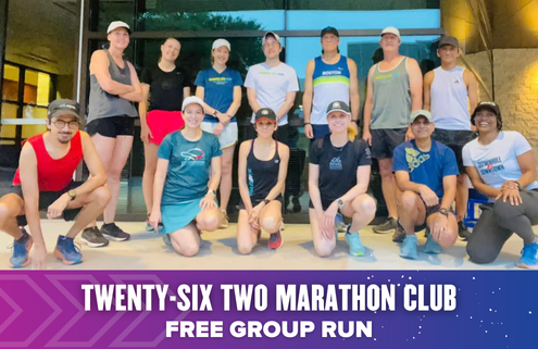 A diverse group of thirteen runners poses and smiles together outside a building. A purple banner below reads: "TWENTY-SIX TWO MARATHON CLUB FREE GROUP RUN"—kicking off launch week with Austin Marathon excitement. Austin Marathon Half Marathon & 5K