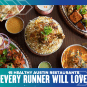 An overhead view of colorful Indian dishes—rice, curry, naan, and grilled skewers—on a wooden table. The text reads: “15 Healthy Austin Restaurants Every Runner Will Love” from top picks in Austin healthy dining. Austin Marathon Half Marathon & 5K