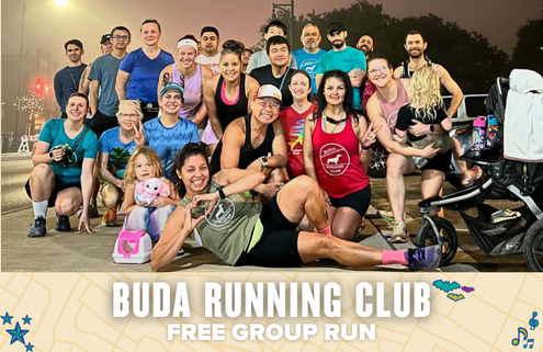 A diverse group of smiling people poses together outdoors before a Buda Running Club group run, with some making playful gestures. Text below reads: "Buda Running Club Free Group Run" on a decorated banner. Austin Marathon Half Marathon & 5K