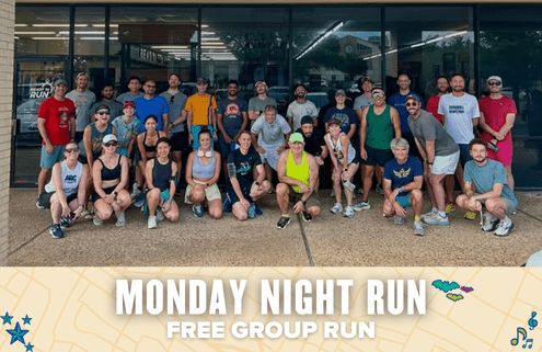 A large group of runners in athletic wear pose and smile together outside a building. Text below reads, "Monday Night Run — Free Group Run" against a decorative background, inviting all to join this welcoming community event. Austin Marathon Half Marathon & 5K