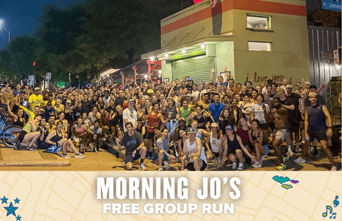 A large, diverse group of people pose together outside a brightly lit building at night. A banner at the bottom reads, “Morning Jo’s Free Group Run,” with a map and playful icons as the background. Join Morning Jo's for a free run!. Austin Marathon Half Marathon & 5K