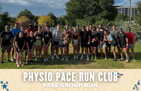 A large group of smiling people in athletic wear pose together outdoors on grass at the Physio Pace group run, some holding water bottles or a small dog. The banner reads "Physio Pace Run Club Free Group Run," with trees and buildings in the background. Austin Marathon Half Marathon & 5K