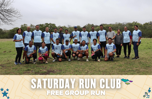A group of people in matching “Saturday Run Club” shirts pose outdoors on grass for a group photo. A banner below highlights the free group run, with music and map icons welcoming all to join Saturday Run Club. Austin Marathon Half Marathon & 5K