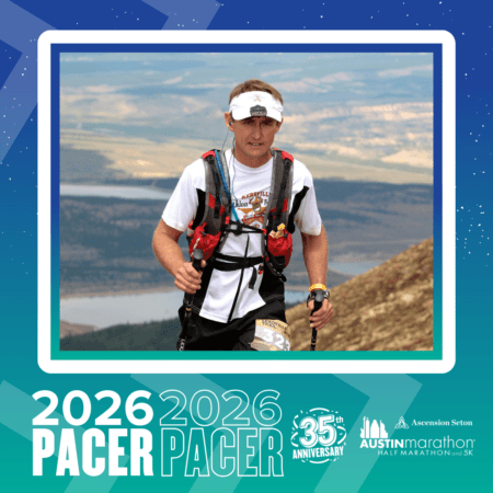 A runner wearing a hydration vest, sunglasses, and a white cap runs uphill on a trail with a scenic lake and hills in the background. Text reads