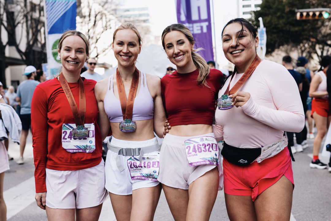Four runners smiling, showing race medals Four runners smiling, showing race medals