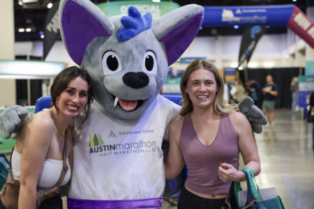 Two women smiling with Austin Marathon mascot Two women smiling with Austin Marathon mascot