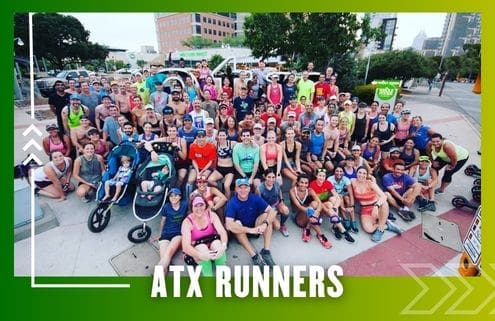 A large, diverse group of runners from the Buda Running Club poses together outdoors on a city sidewalk. Some have strollers, and all wear athletic clothing. The text "ATX RUNNERS" is displayed at the bottom of the image. Austin Marathon Half Marathon & 5K
