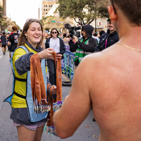 Race volunteer handing medals to runner