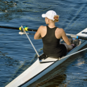 Woman rowing single scull on calm water