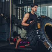 Man flipping large tractor tire in gym