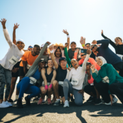 A diverse group of runners wearing race bibs smile and pose for a cheerful group selfie outdoors under a bright sky, proving that when motivation fades, camaraderie and shared celebration keep the spirit of the race alive. Austin Marathon Half Marathon & 5K