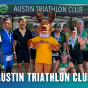 A group of smiling athletes, some in cycling gear and medals, pose with a person in a moose mascot costume under an “Austin Triathlon Club” tent—celebrating after an energetic South Austin Group Run. Blue border with white text. Austin Marathon Half Marathon & 5K