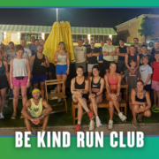 A group of people of various ages pose together outdoors at night in South Austin, dressed in athletic wear, with a banner at the bottom that reads “Be Kind Run Club.” It’s clear this group run is part of the local Rise and Run community spirit. Austin Marathon Half Marathon & 5K