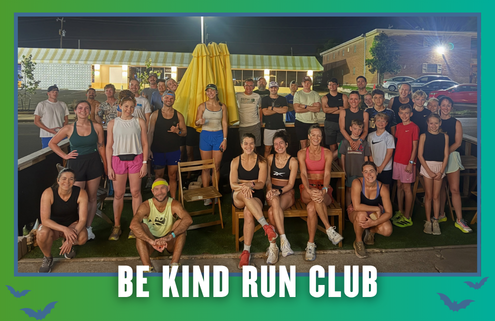 A group of people of various ages pose together outdoors at night in South Austin, dressed in athletic wear, with a banner at the bottom that reads “Be Kind Run Club.” It’s clear this group run is part of the local Rise and Run community spirit. Austin Marathon Half Marathon & 5K