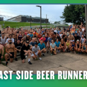 A large group of people pose outdoors in athletic wear, gathered closely together, smiling at the camera. Text at the bottom reads “EAST SIDE BEER RUNNERS” on a teal border with small bats. This vibrant South Austin group run captures the spirit of Rise and Run—friends coming together for fitness and fun. Austin Marathon Half Marathon & 5K