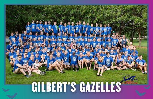 A large group of people wearing matching blue shirts sits and stands together outdoors on grass, smiling at the camera during a Group Run. The text “GILBERT’S GAZELLES” is displayed at the bottom of the image. Austin Marathon Half Marathon & 5K