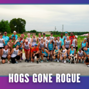 A large group of runners in athletic gear pose together outdoors on a road in South Austin, smiling and celebrating. Text reads “HOGS GONE ROGUE” in bold letters at the bottom of the image, capturing the excitement of this group run during KickOff Week. Austin Marathon Half Marathon & 5K