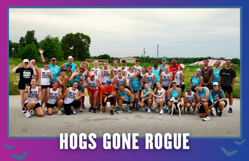 A large group of runners in athletic gear pose together outdoors on a road in South Austin, smiling and celebrating. Text reads “HOGS GONE ROGUE” in bold letters at the bottom of the image, capturing the excitement of this group run during KickOff Week. Austin Marathon Half Marathon & 5K