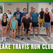 A group of thirteen people in athletic wear smile outside a building, posed for a group run. Text at the bottom reads “Lake Travis Run Club” over a green and blue border with bat graphics, highlighting the kickoff week atmosphere reminiscent of the Leanderthal Runners Club spirit. Austin Marathon Half Marathon & 5K