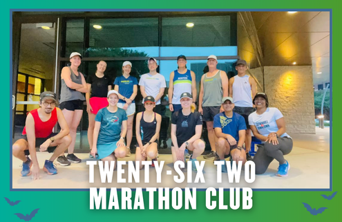 Thirteen runners pose together in athletic gear outside a building, ready for a group run. “Twenty-Six Two Marathon Club” is written at the bottom. The photo, possibly taken during KickOff Week with Mueller Run Club, has a green and blue border with small bat icons in the corners. Austin Marathon Half Marathon & 5K