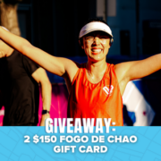 A smiling woman in a visor and running gear raises her arms at a race. Text overlay reads: “GIVEAWAY: 2 $150 FOGO DE CHAO GIFT CARD.” Blue banner with bats is at the bottom. Enter now for a chance to win your entry back and score a handy travel shoes bag!. Austin Marathon Half Marathon & 5K
