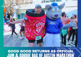 A runner in a strawberry jam costume stands next to a person in a blue wolf mascot suit at the Austin Marathon, sponsored by Ascension Seton, with cheering participants in the background. Text below promotes GOOD GOOD as the official jam and goodie bag. Austin Marathon Half Marathon & 5K